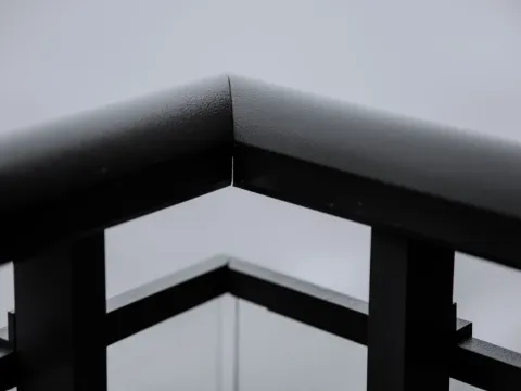 Angle d'une main courante en acier noir mat reposant sur ses montants, finition poudrée régulière