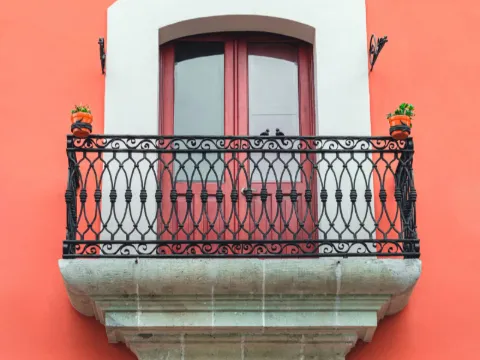Porte-fenêtre à garde-corps en fer forgé noir sur un mur corail uni