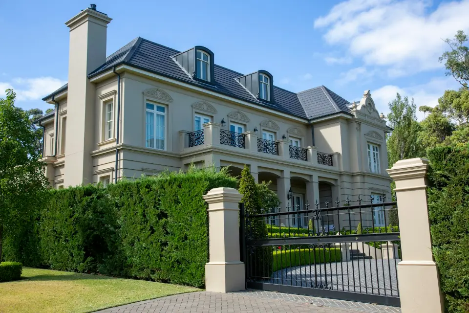 Grand portail en fer noir à pointes de lance devant une villa de style château
