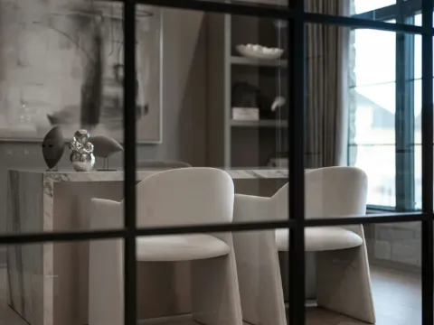 Verrière à carreaux d'acier noir au premier plan devant une salle à manger en marbre