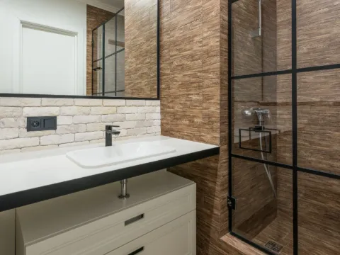 Paroi de douche à carreaux d'acier noir dans une salle de bain aux tons bois