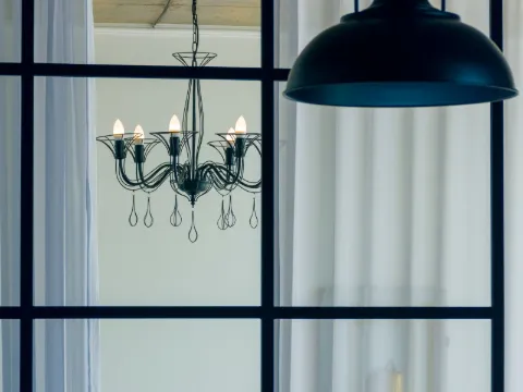 Verrière à grands carreaux d'acier noir donnant sur une chambre, lustre et suspension noire